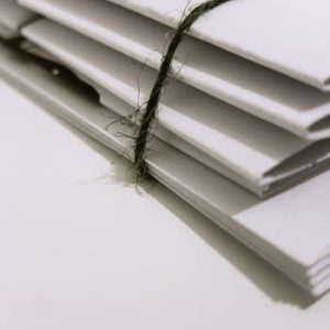 Pile of white envelopes tied with a green string, showcasing a minimalist design.