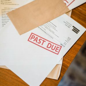 Photograph showing past due and bankruptcy documents on a wooden table.